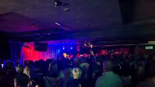 a musician singing on stage in a crowded club