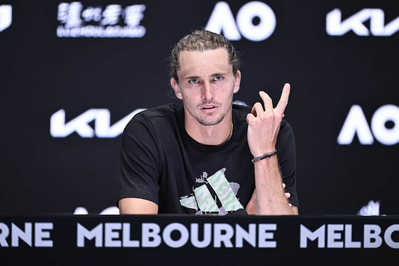 A man looking looking serious, gestures with his hand.