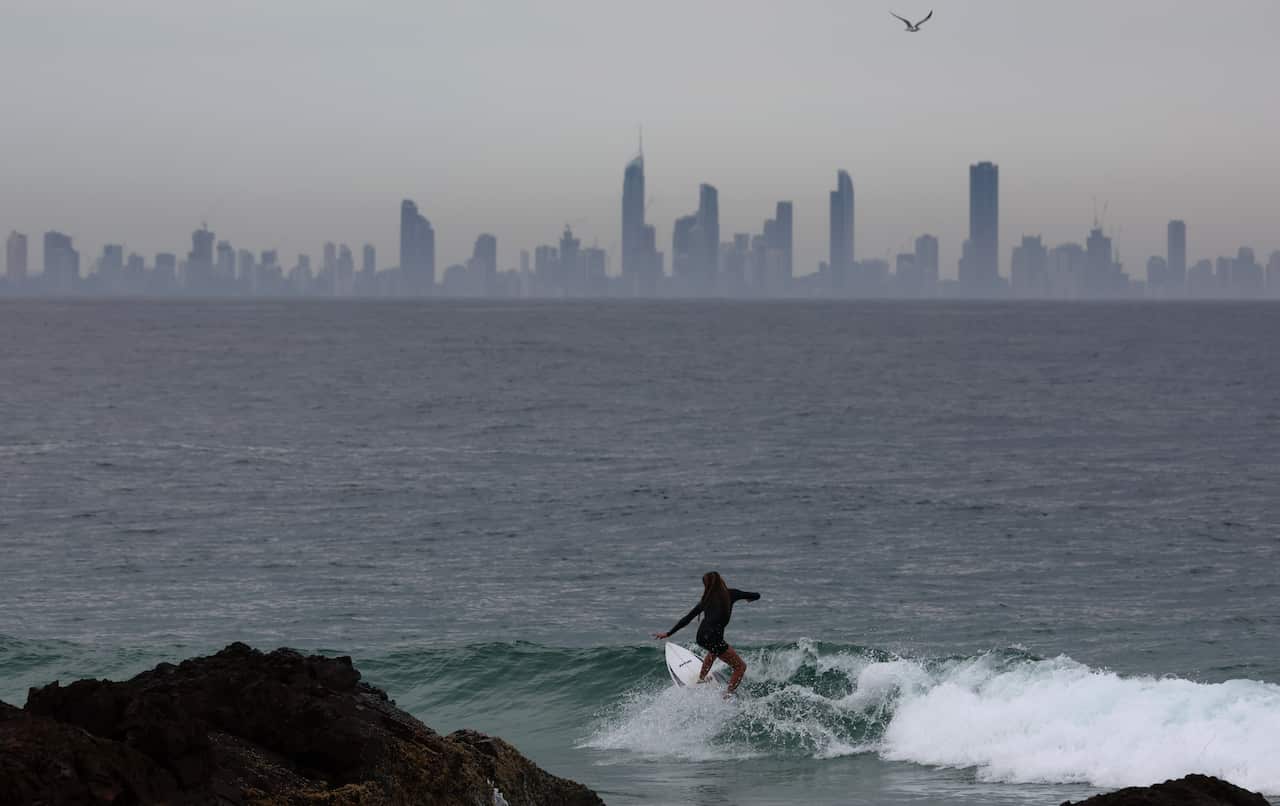 A person surfing, a city skyline can be seen in the background. 