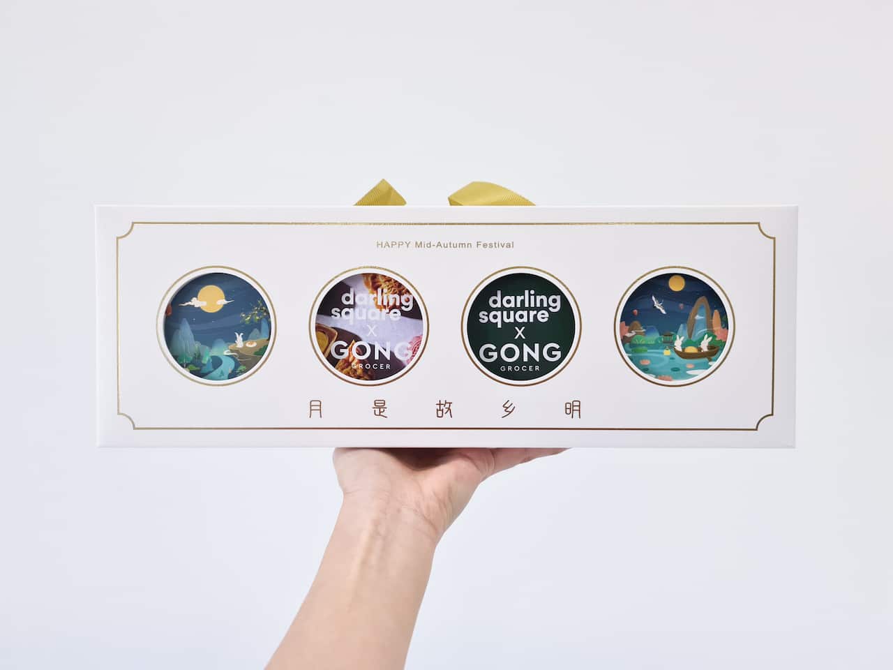 A hand holding a box of mooncakes.