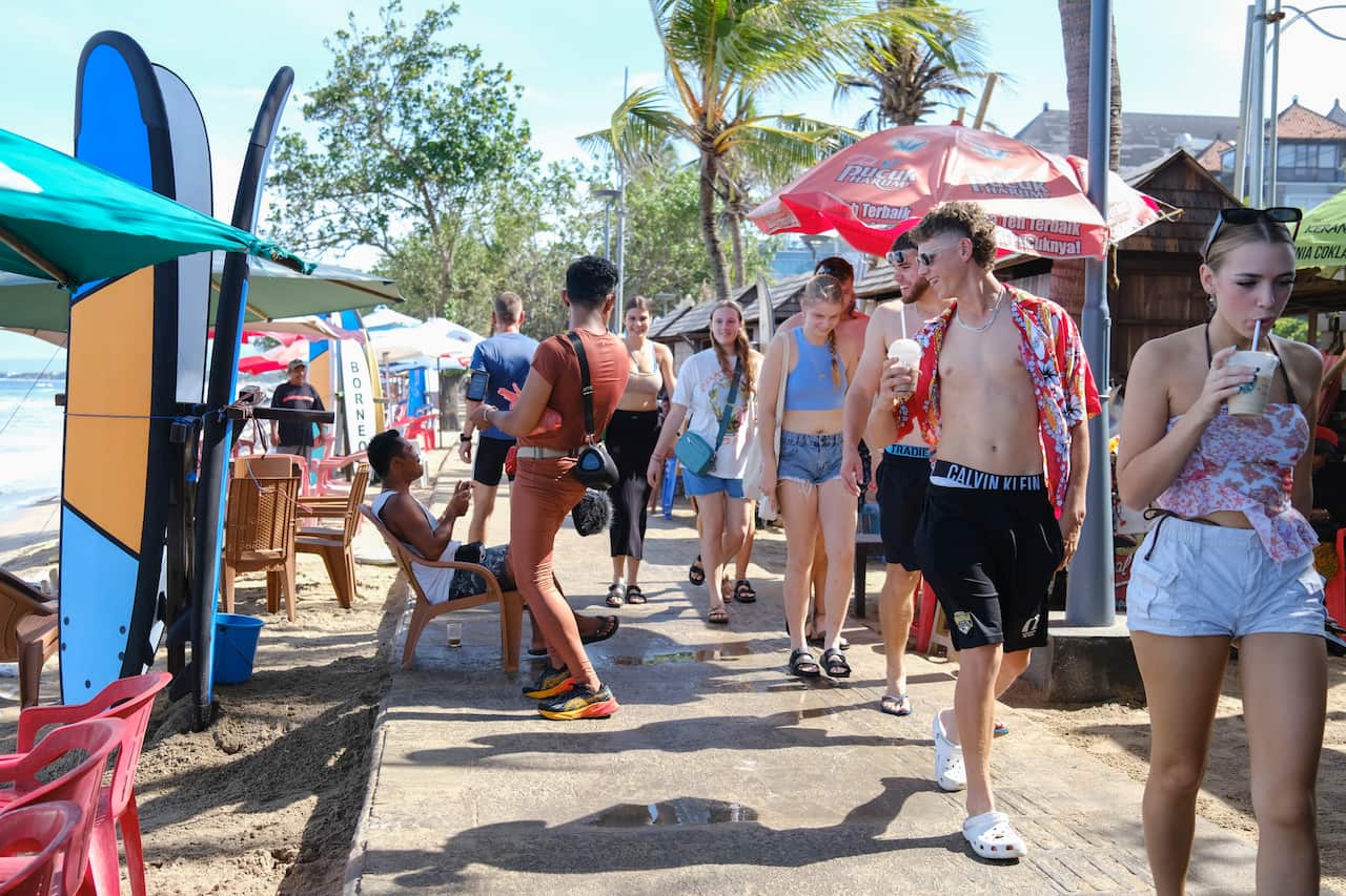 Tourists walking along by the beach in Kuta, Bali. 