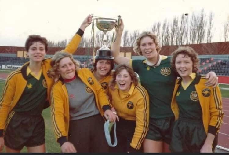 A group of women with Australian tracksuits and a trophy