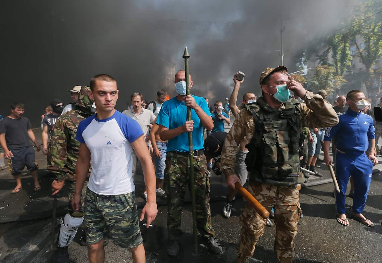 Activists clash with Ukrainian National guard soldiers in front of a burning barricade