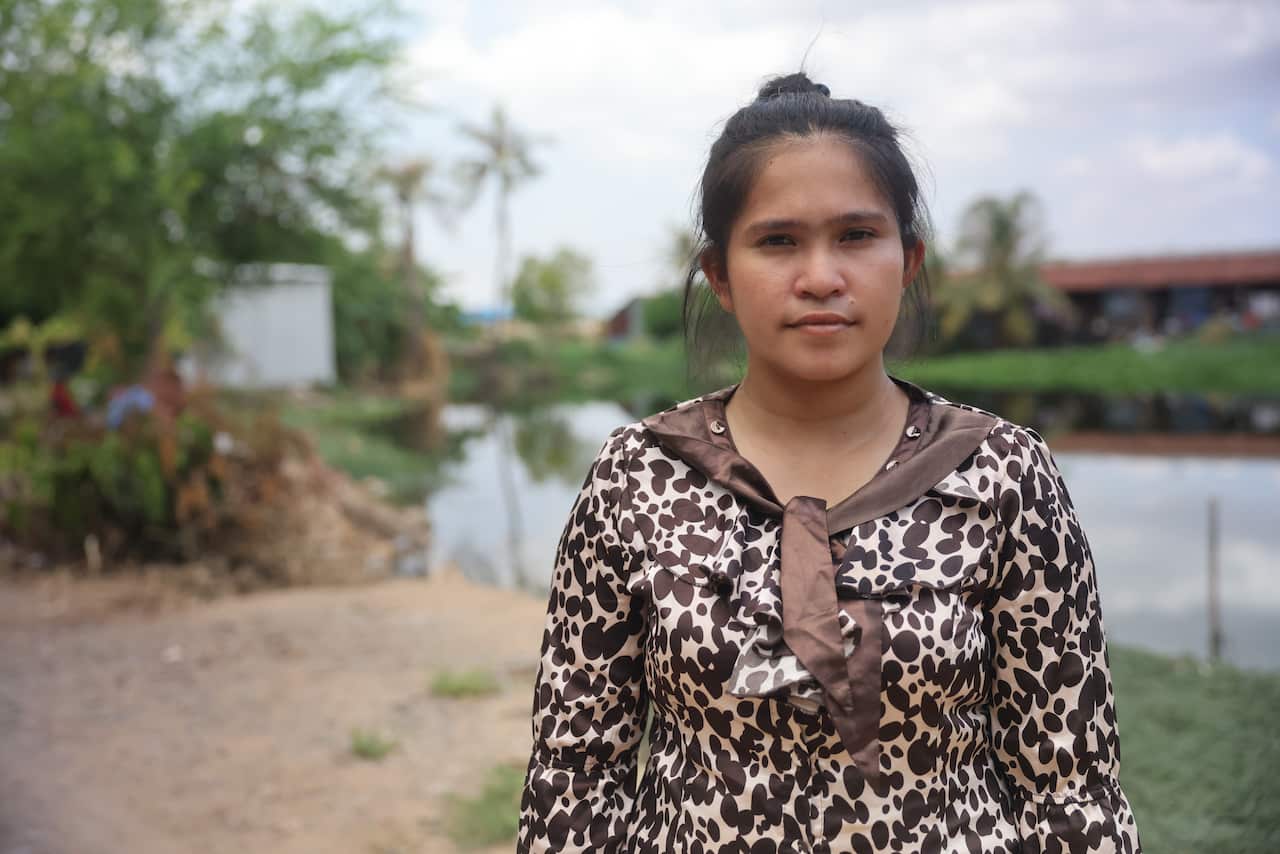 A Cambodian woman wearing a brown and white patterned top 