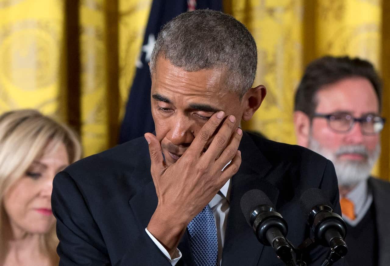 Former US president Barack Obama wipes tears from his eyes as he addresses the media.