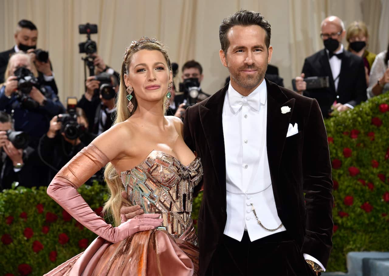 Actors Blake Lively (left, wearing a gold-coloured ball gown) and Ryan Rynolds (wearing a dinner suit with white bow tie) on the Met Gala red carpet.