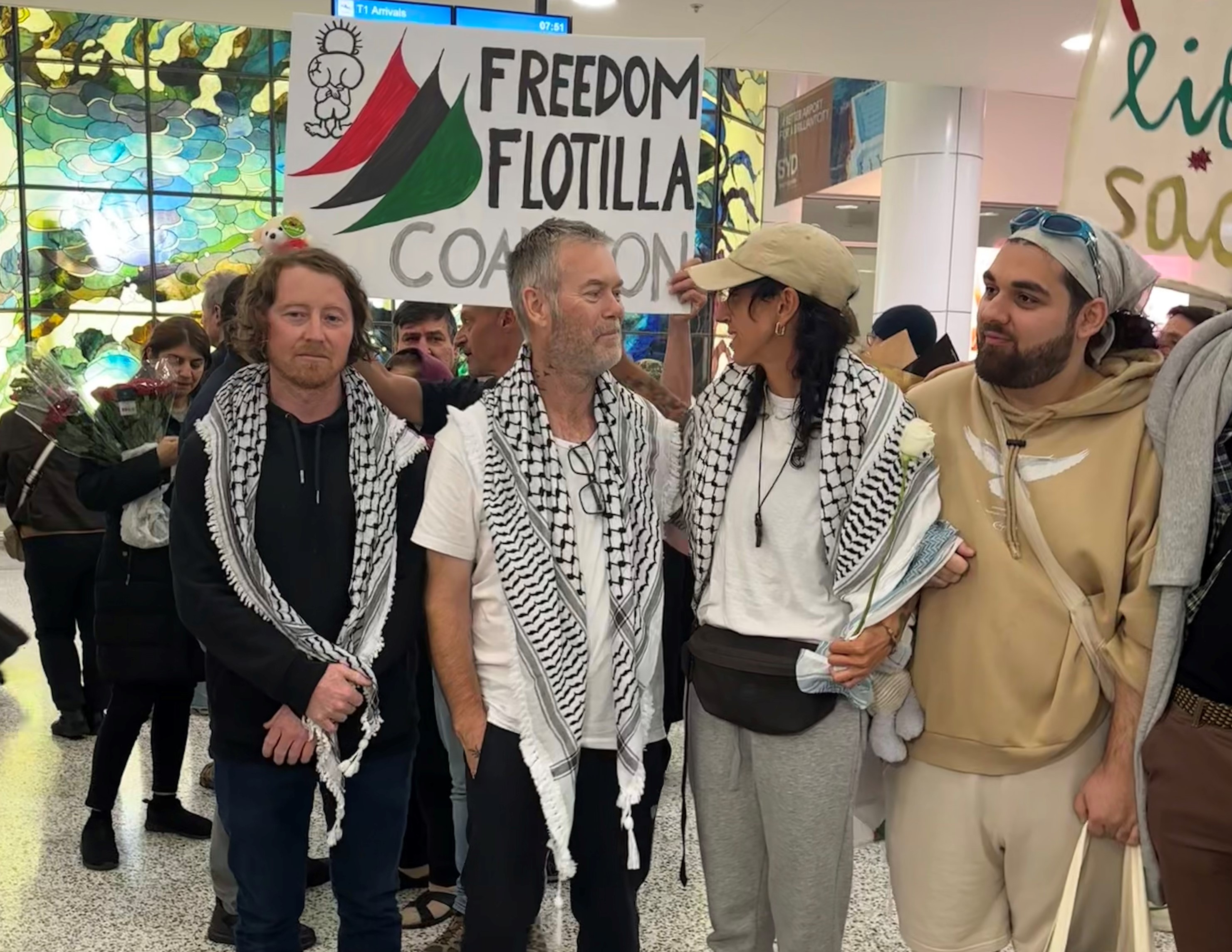 A group of people standing in a row with banners behind them.