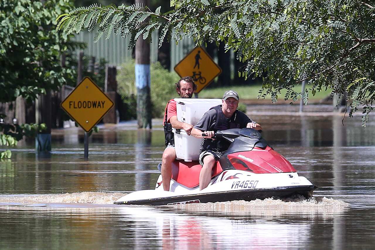 Tony Wartlier (right) helps a flooded resident evacuate his flooded house with animals, in Logan, south of Brisbane, as the suburb reached its peak, Tuesday, 1 March, 2022. 