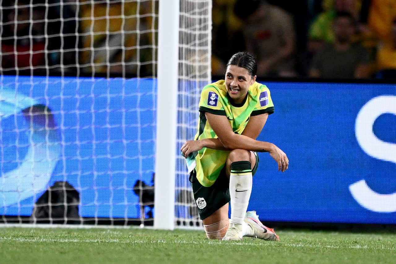 A photo of Matildas captain Sam Kerr at the 2026 Women's Asian Cup final. Kerr is dressed in her team kit, on one knee with her arms folded over her leg. She looks exasperated, after another goal has failed to materialise.