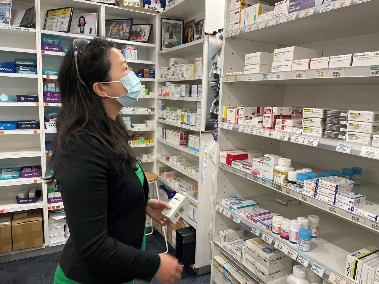 A woman looks at a shelf of medications in a pharmacy