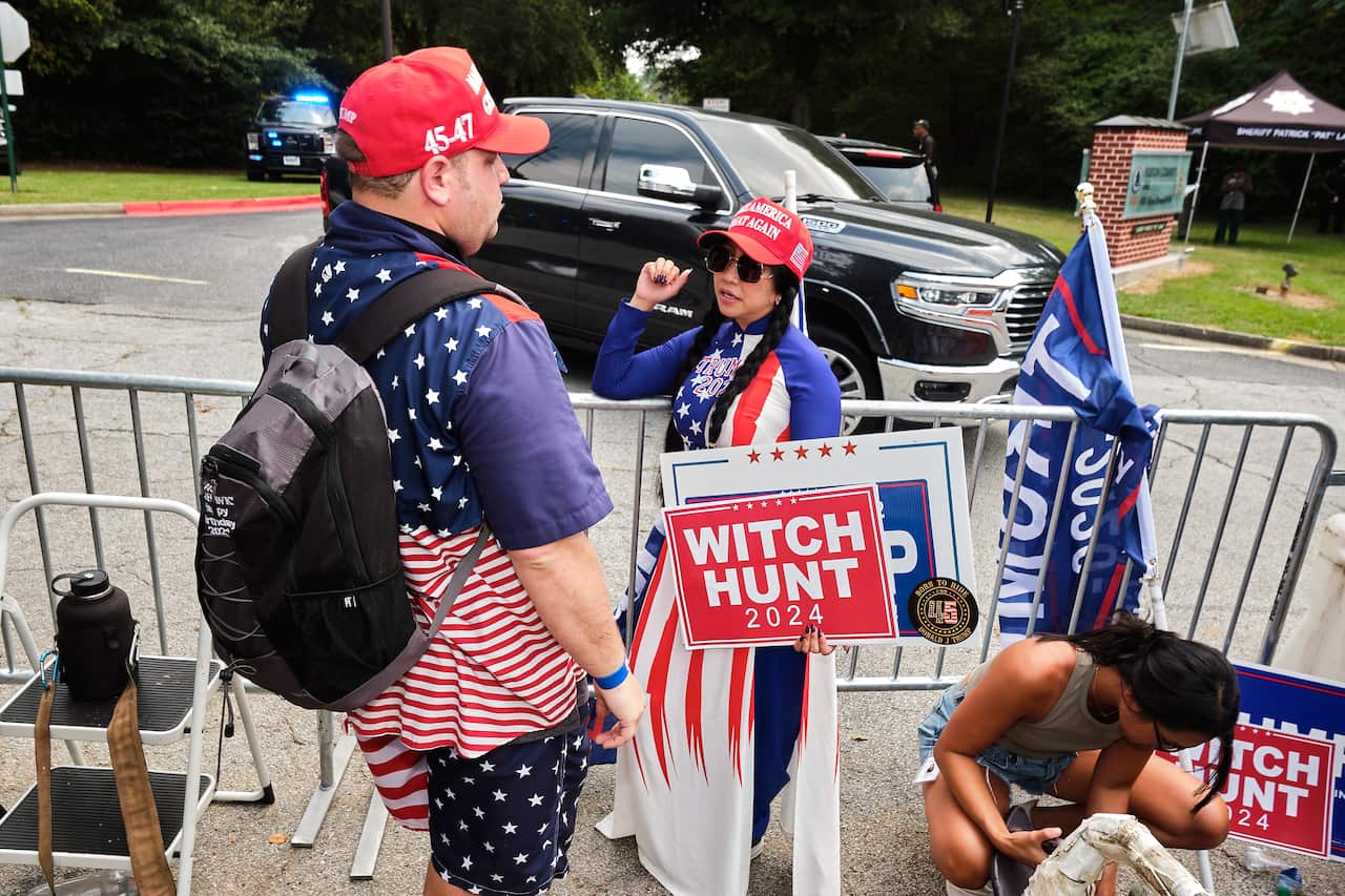 Wearing United States flag-patterned clothing and "Make America Great Again" caps, supporters of Donald Trump gather outside Fulton County Jail in Atlanta, Georgia.