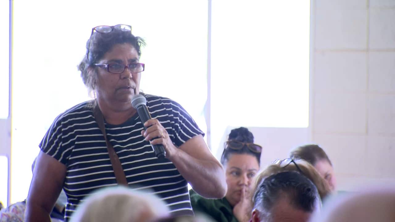 A woman stands with a microphone. 