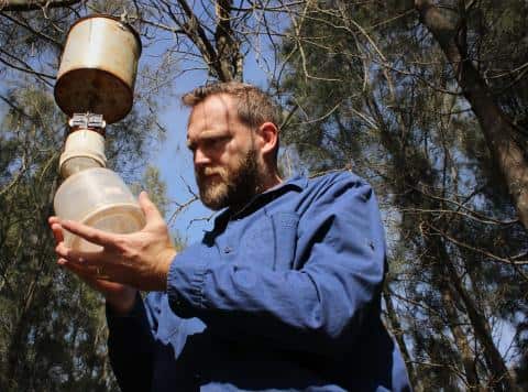 Man standing in nature holding a mosquito trap