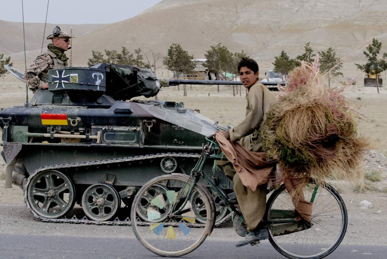 An Afghan boy passes German ISAF forces while on patrol along the Jalalabad highway on the outskirts of Kabul, Afghanistan on Wednesday Oct 8, 2003.   