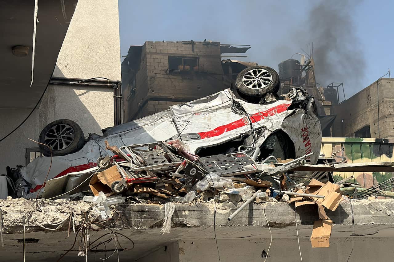 A destroyed ambulance sitting upside down among rubble.
