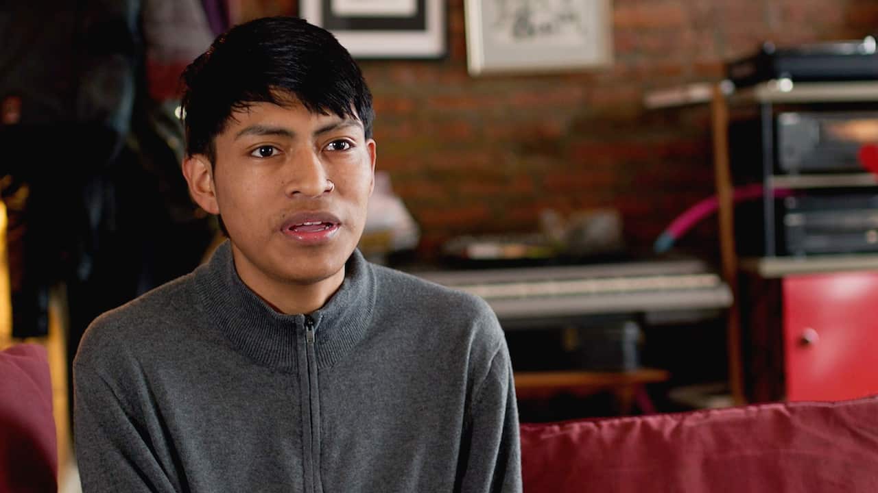 A man in his early 20s wearing a grey zip sweater 