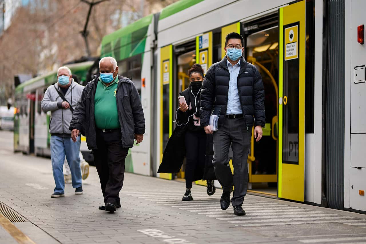 People wearing face masks getting off a tram