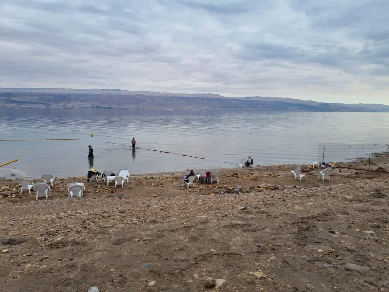A few deckchairs sit, mostly empty, on the edge of a large, still body of water.
