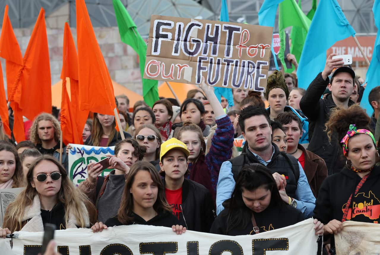 A large group of people standing together, carrying banners and flags. The central banner reads "Fight for our future".