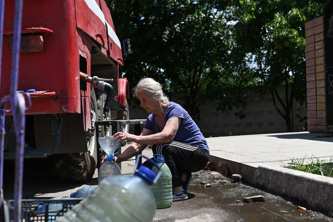 A resident of Lysychansk fills up water jugs from a fire department truck