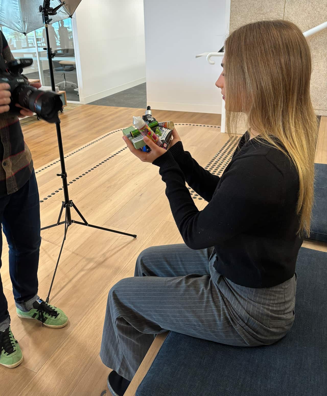 A young woman sits on a bench with a bunch of vaping paraphernalia in her hands.