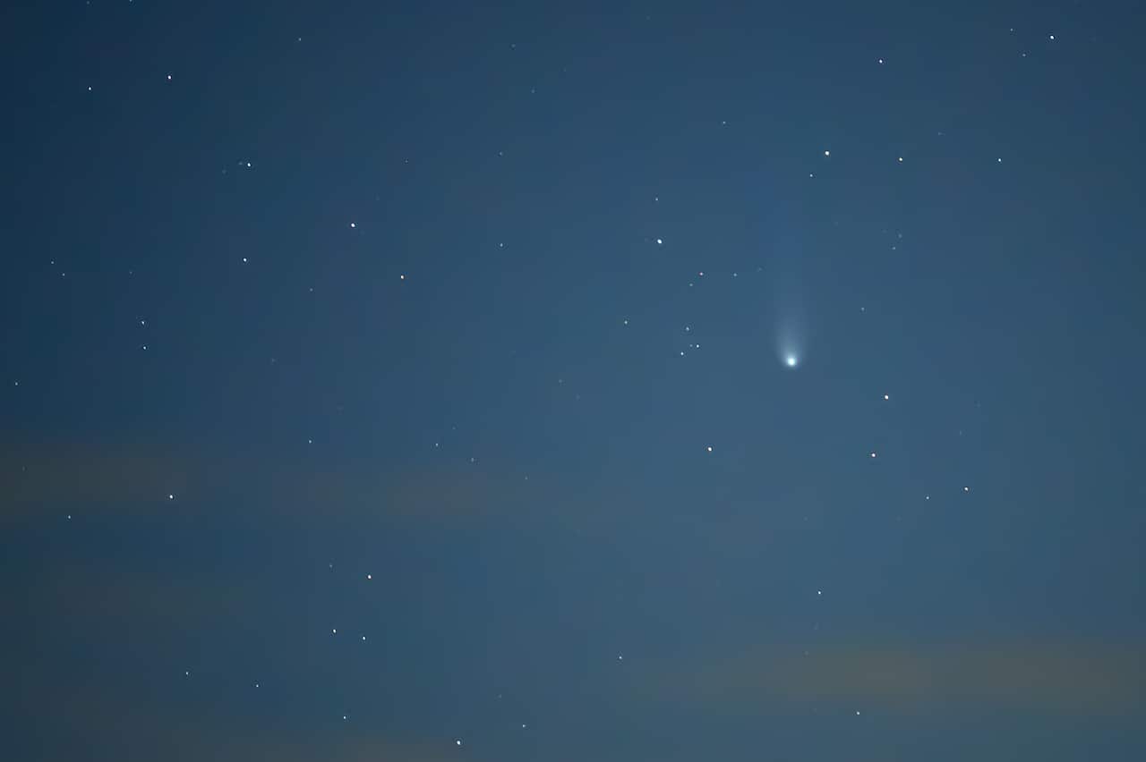 A comet shines prominently against a dark night sky filled with stars.