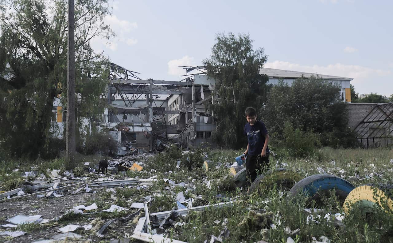 A boy walking outside among debris.