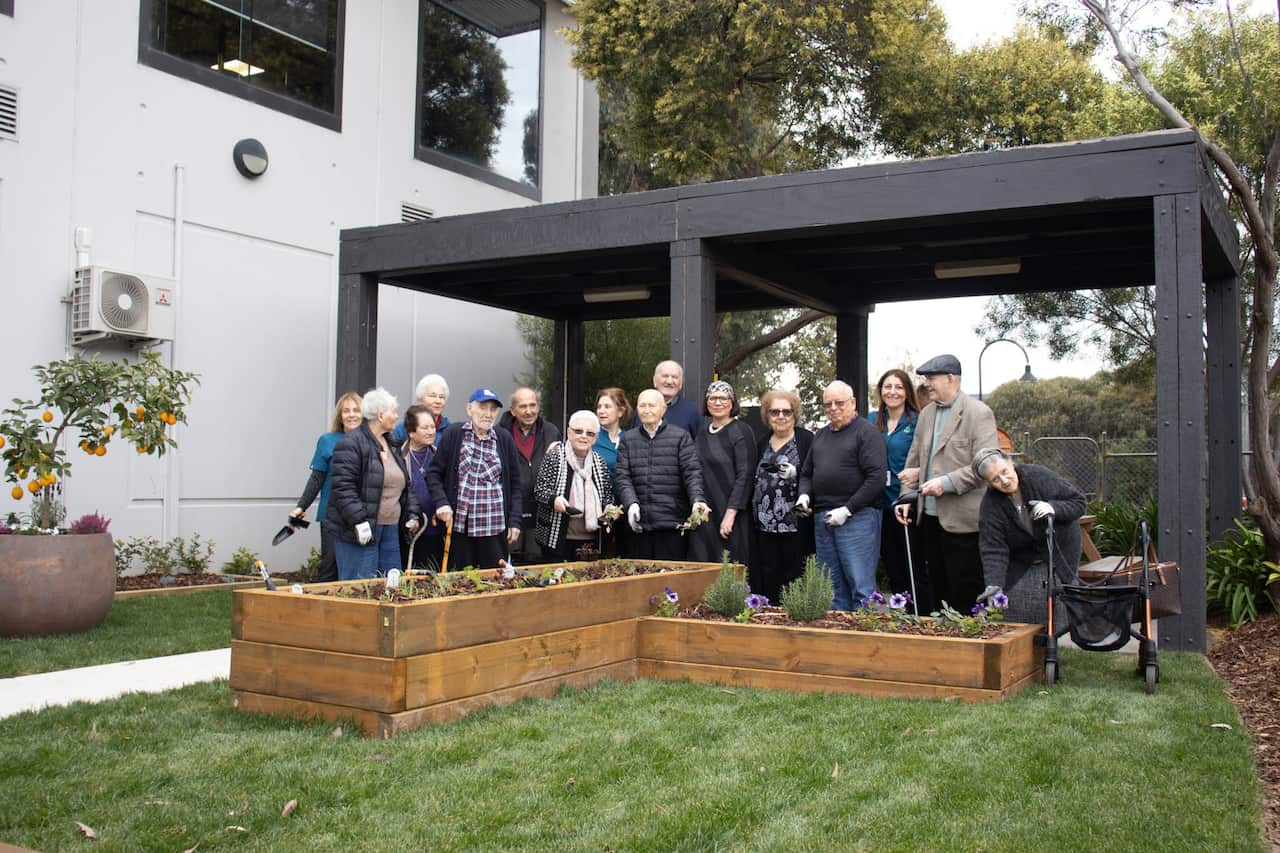 A group of older people stand around a garden