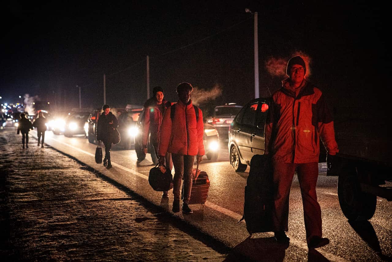 People on foot and in cars move to cross from Ukraine to Poland at the Korczowa-Krakovets border crossing.