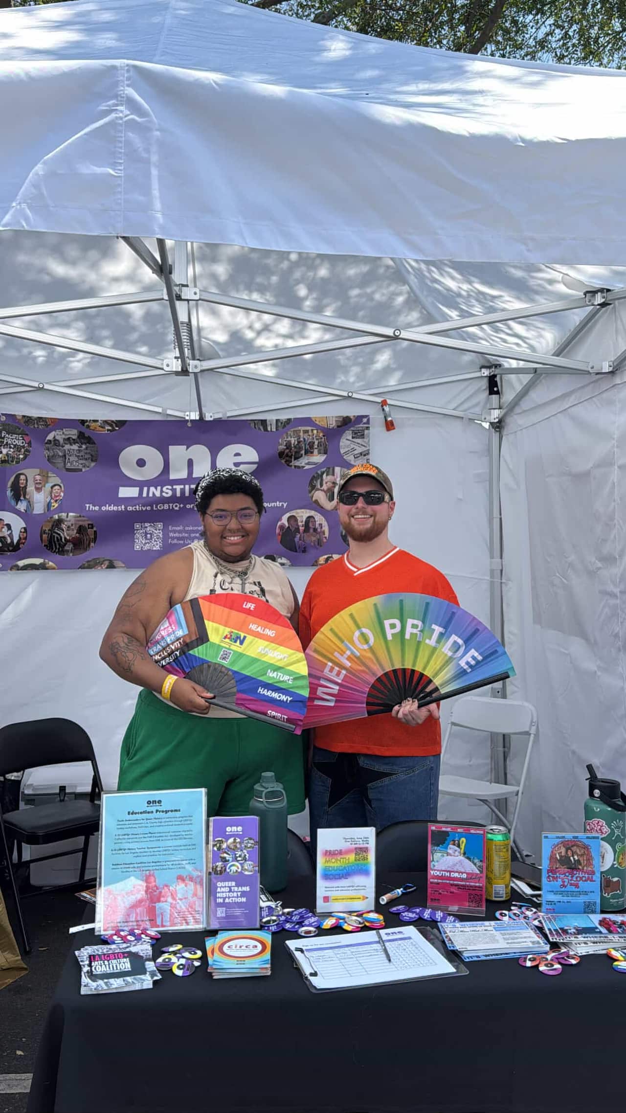 Two people holding rainbow fans.