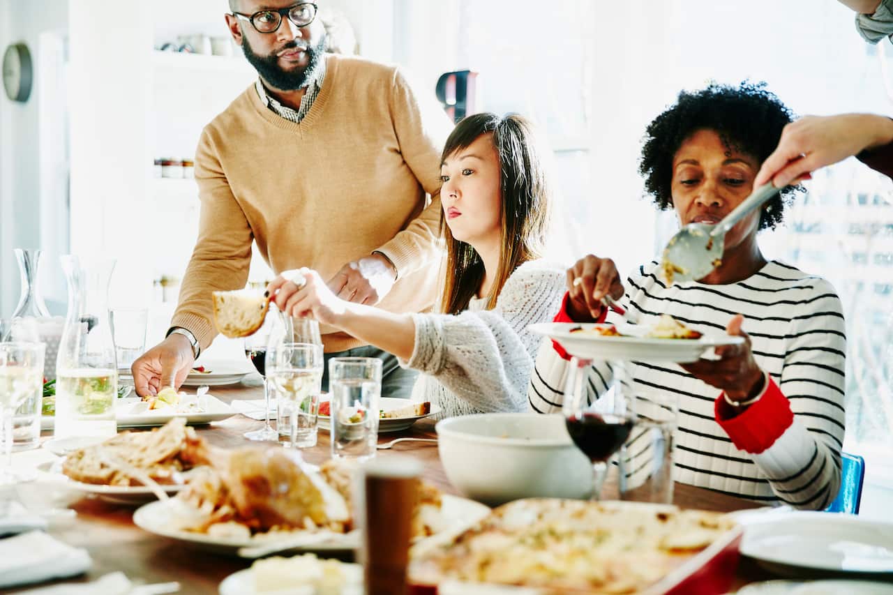 Friends serving each other during holiday meal together