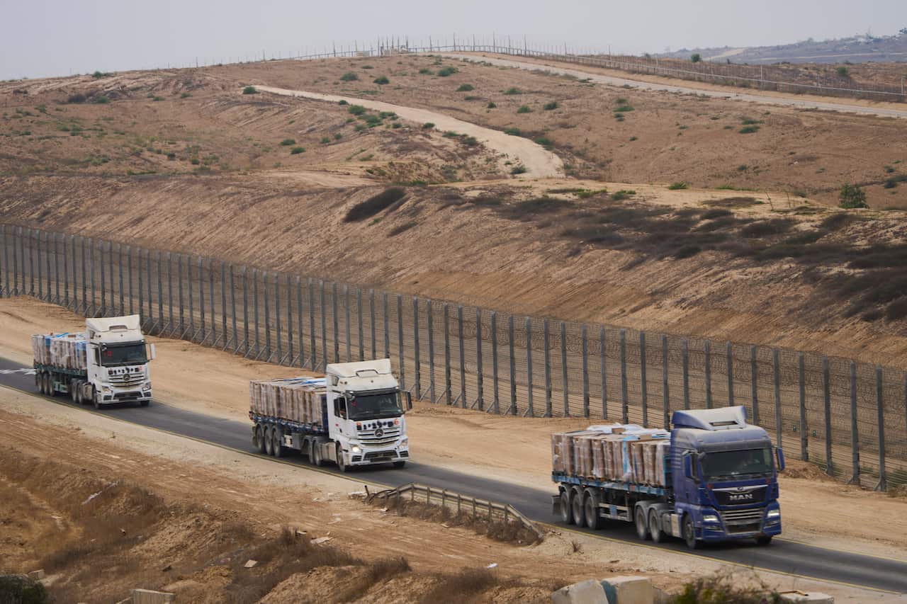 Three trucks driving along a road in the mid-distance