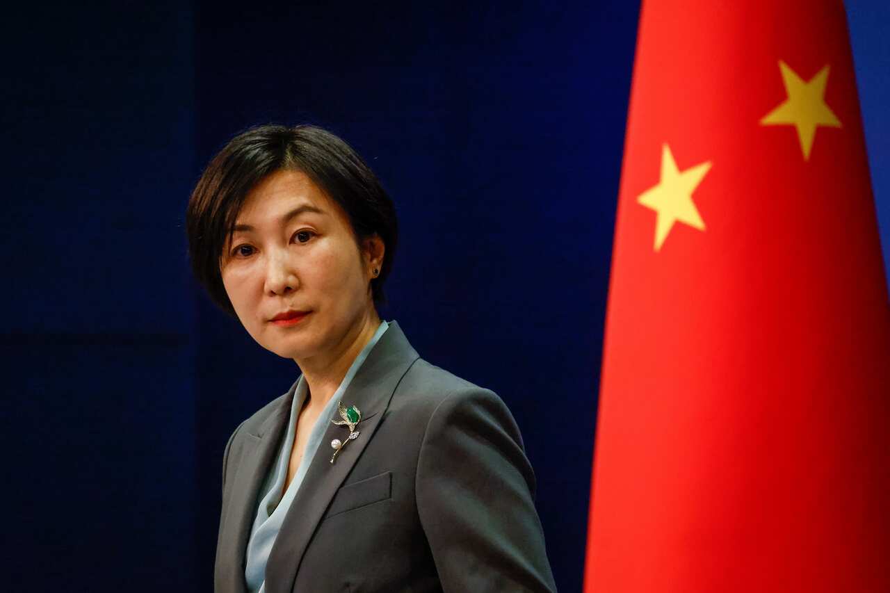 A woman stands in front of a Chinese flag.