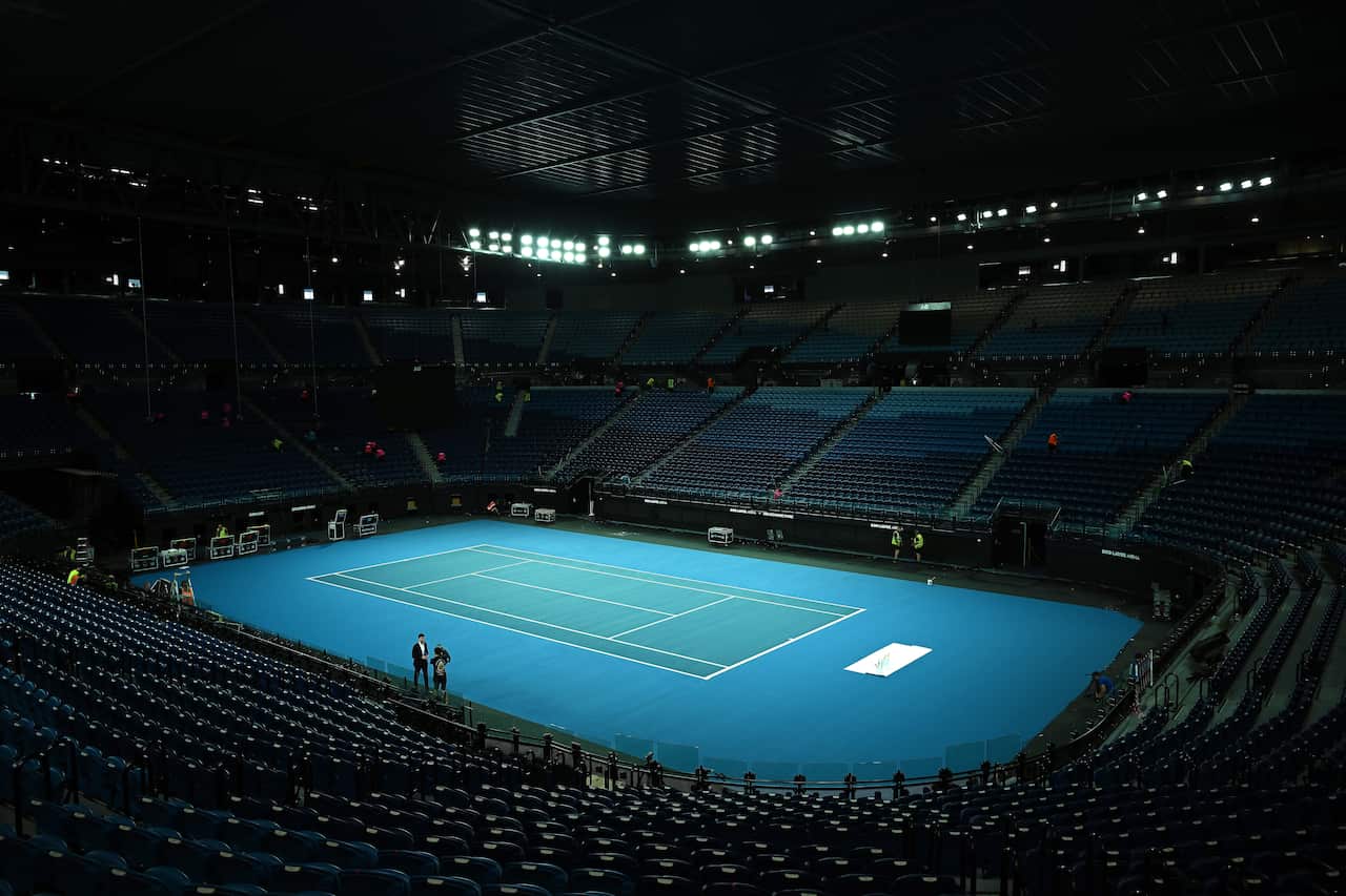 An arena with a blue tennis court and rows of seats around it.
