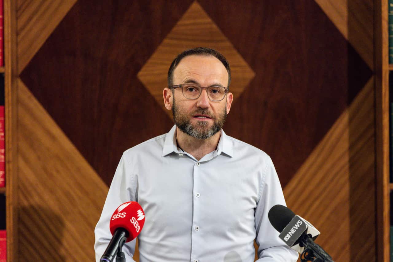 A man speaking in front of microphones.
