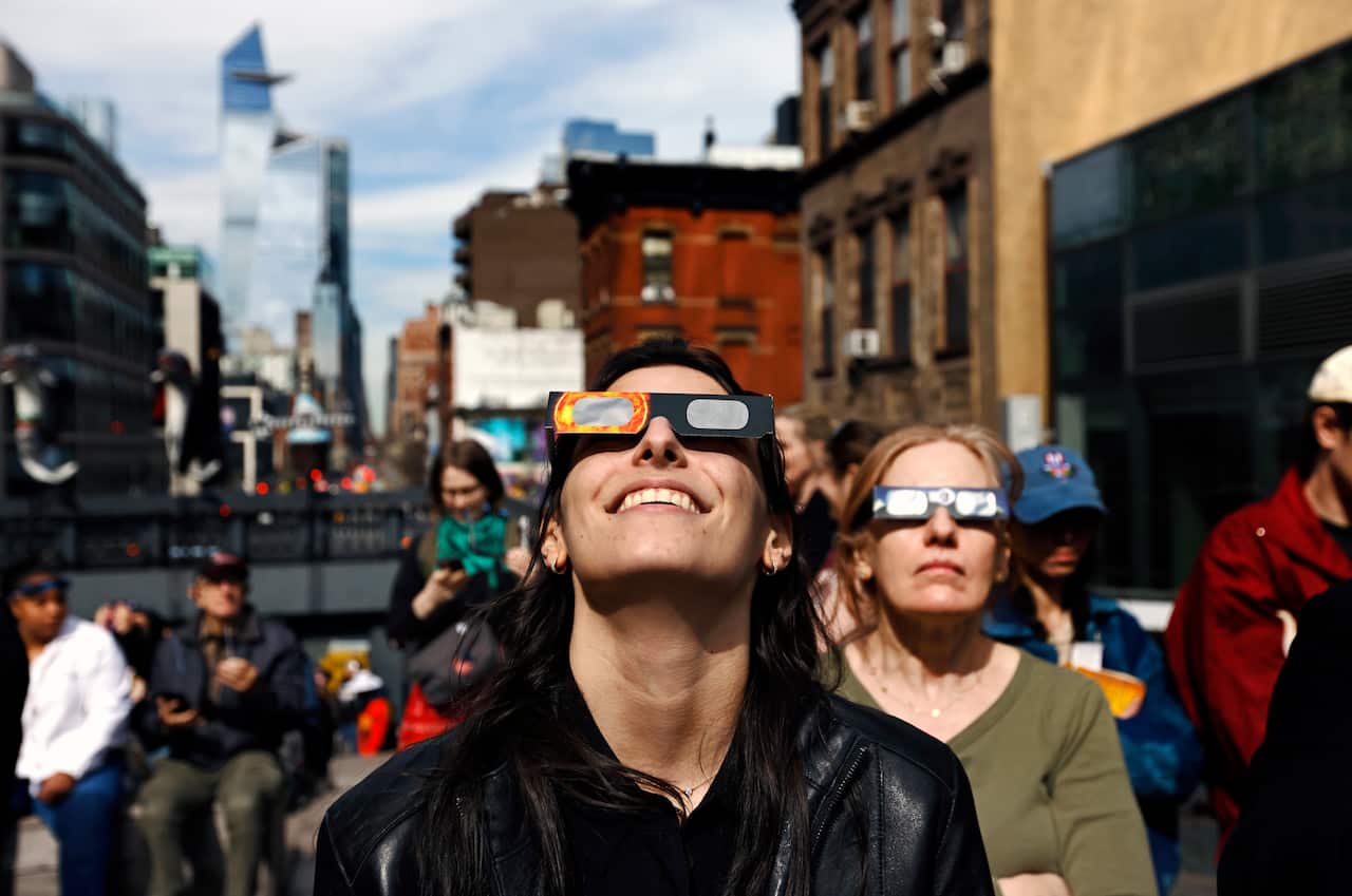 People wearing solar eclipse glasses looking up into the sky