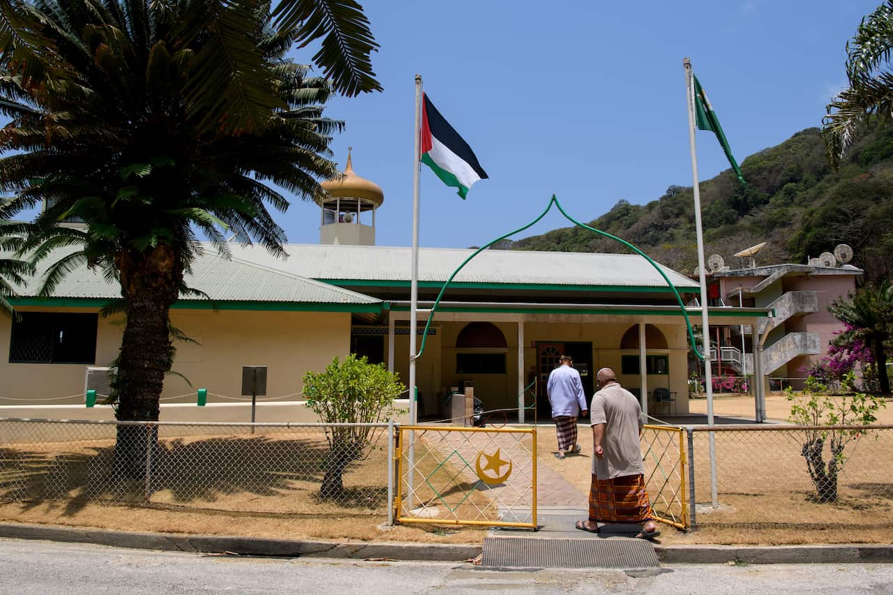 People walking through a gate and toward a building.