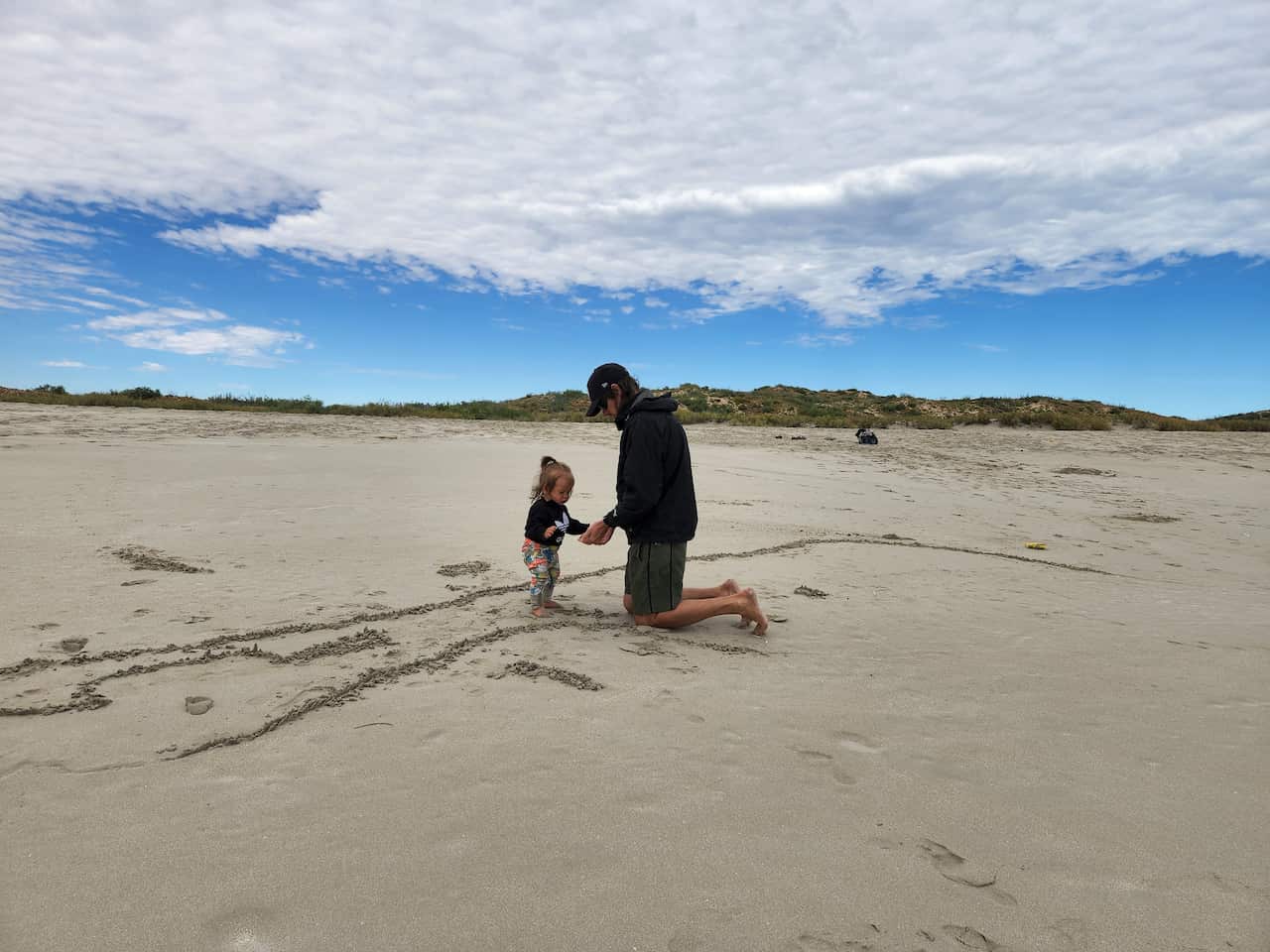 A father playing with his toddler at the beach.