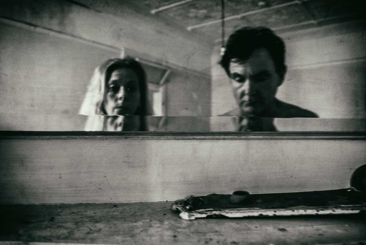 a black and white photo of a woman and a man in an empty room of a run-down building