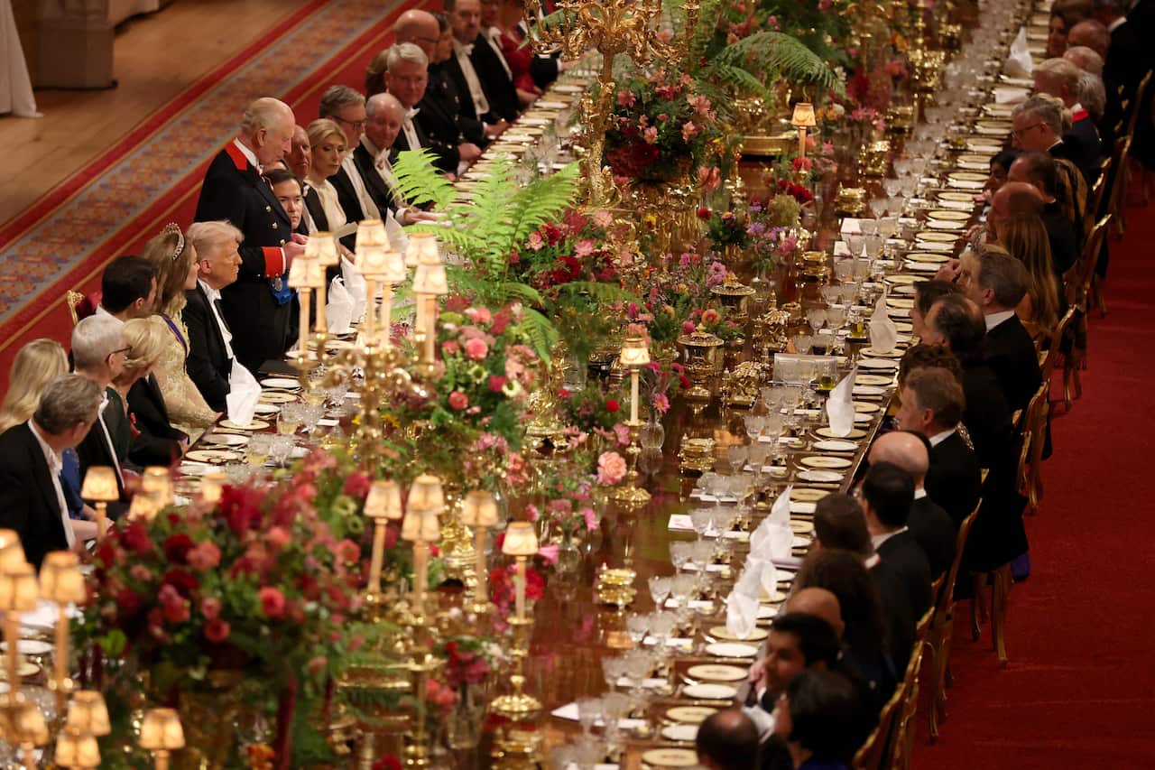 Two large rows of people seated on either side of a large banquet table.