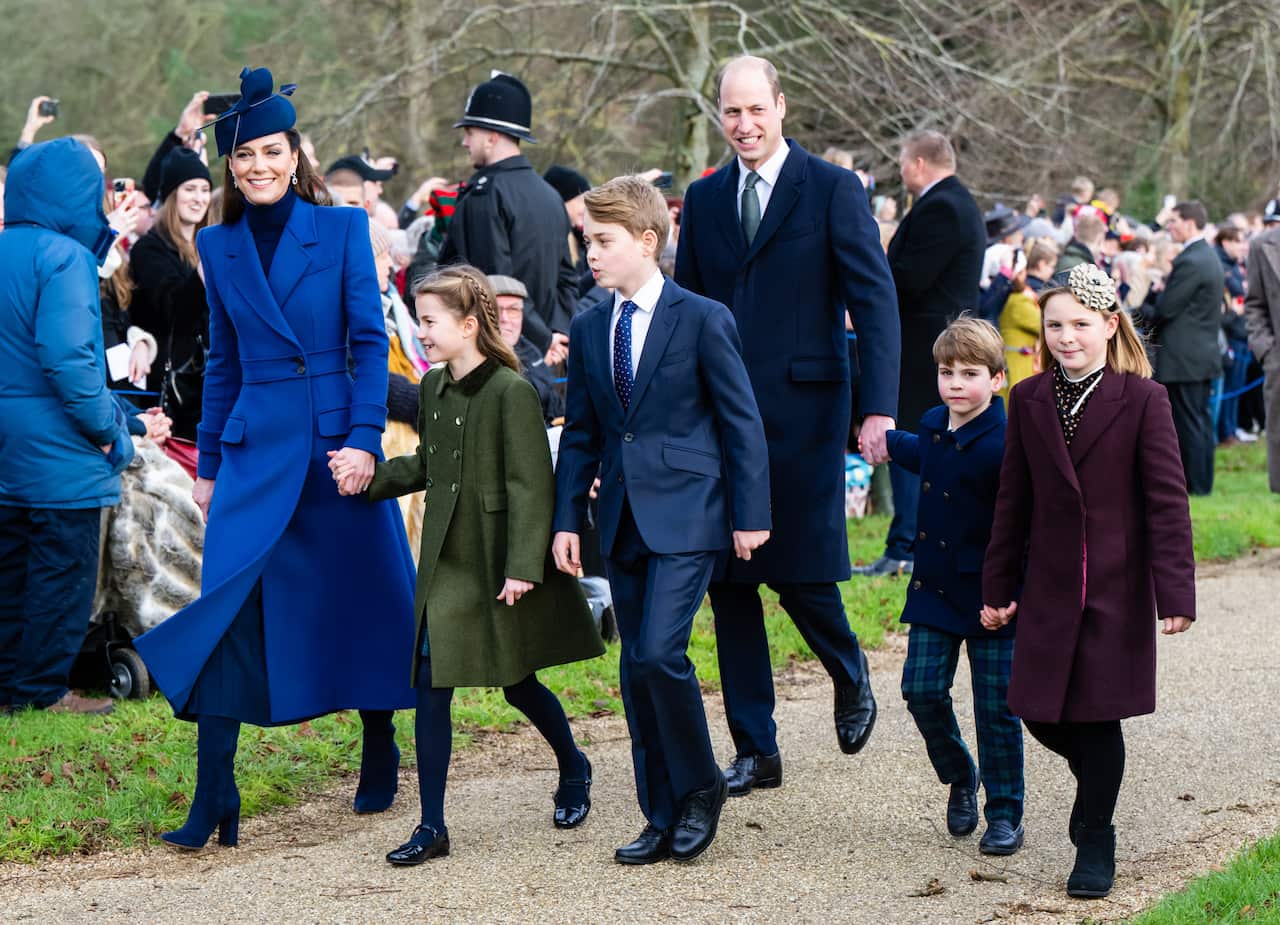 Princess Kate walking with her husband and children with a crowd of onlookers.