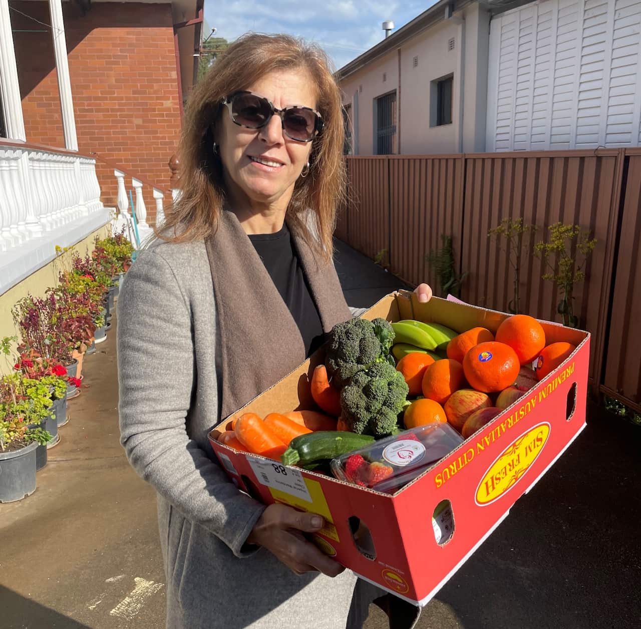 Marsha El Bayeh holding a box of vegetables and fruit 
