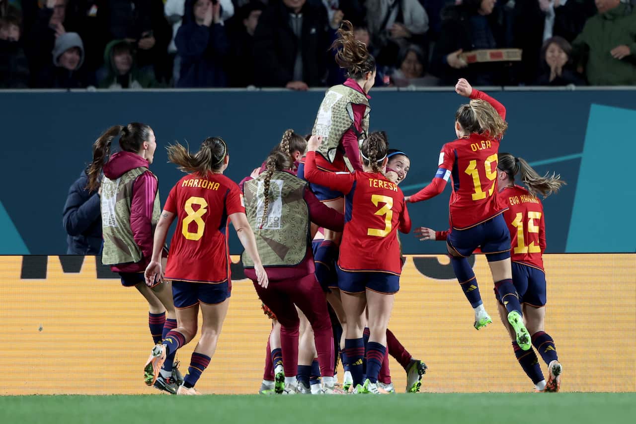 Players of Spain's women's football team cheering and jumping on the field.