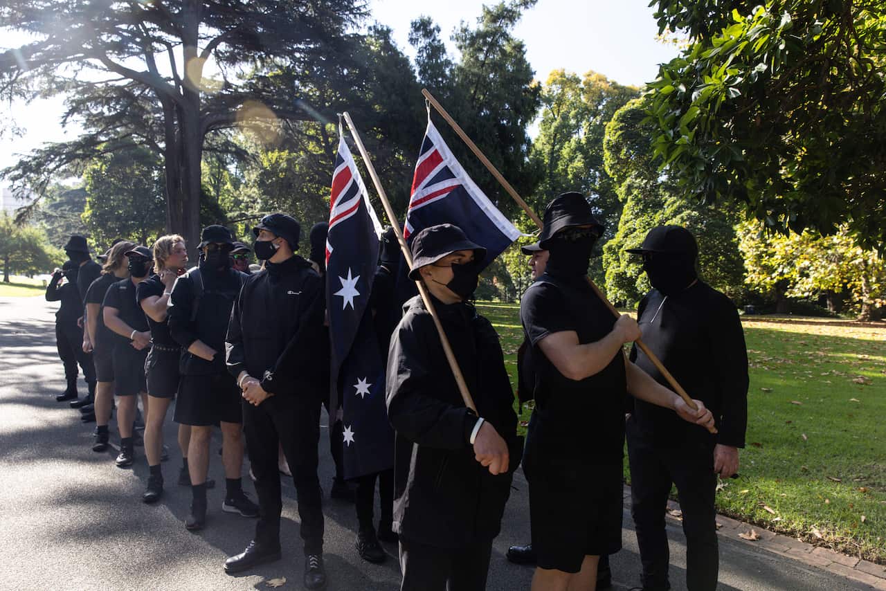 People wearing all black. Two are holding Australian flags.