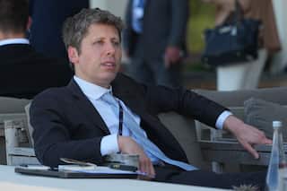 OpenAI CEO Sam Altman in a suit lounging in a chair outside at the G7 summit