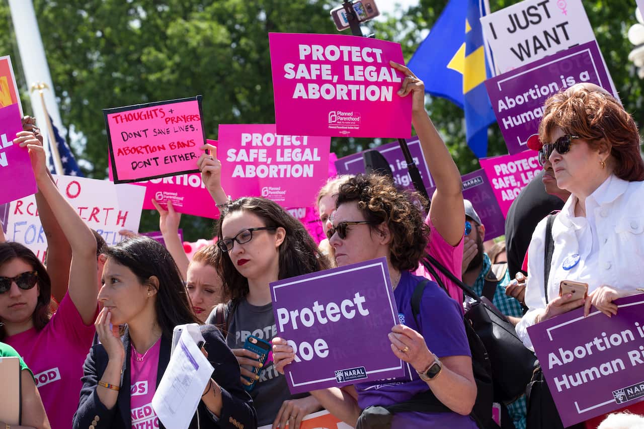 Protestors holding signs reading 'protect Roe' and 'protect safe, legal abortion' at a rally during the day in the US.  