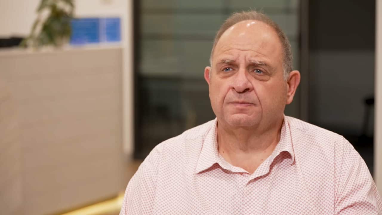 A man in a pink shirt poses for a photo