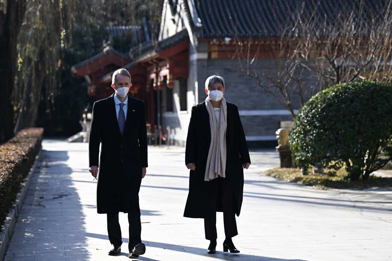 A man and a woman dressed in suits and coats take a walk in Beijing. 