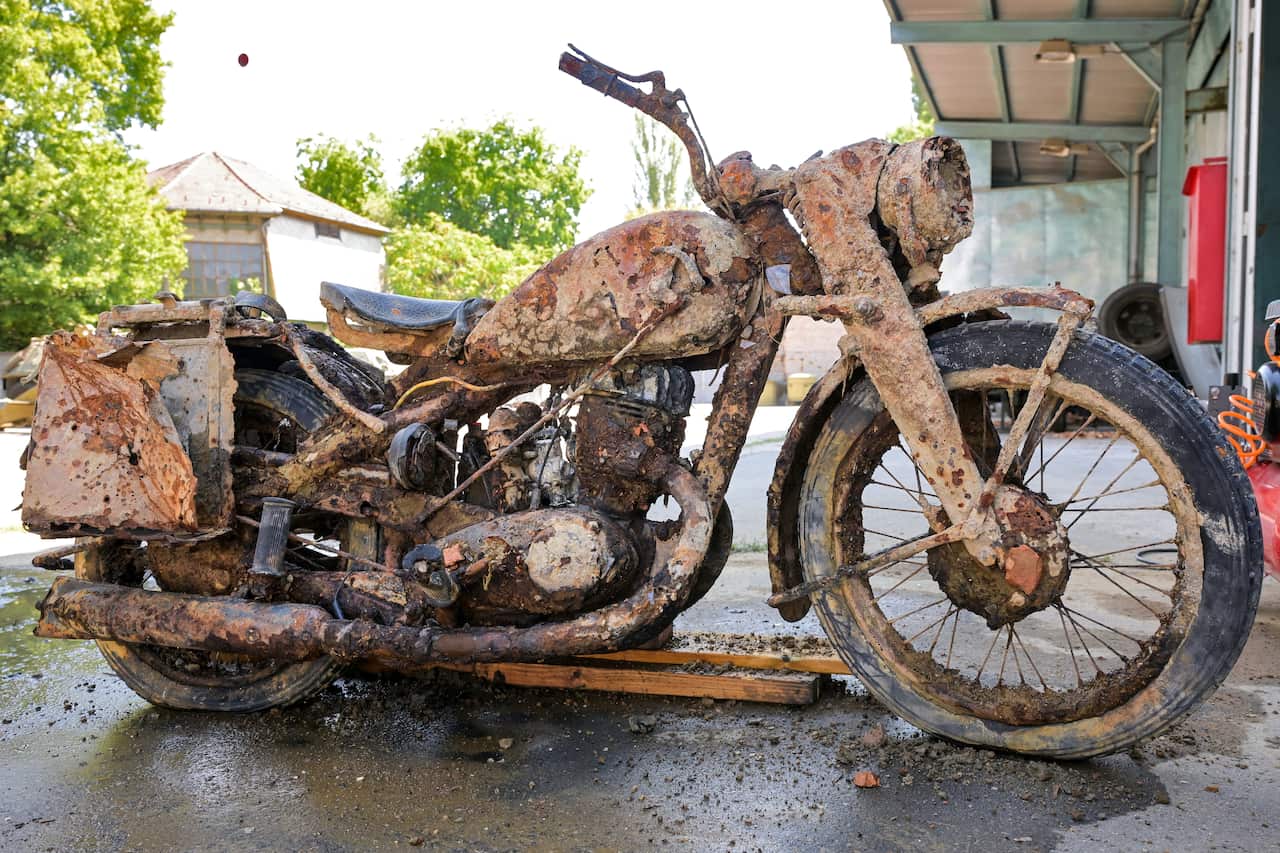 A German World War Two motorcycle covered in mud. It is standing up outside