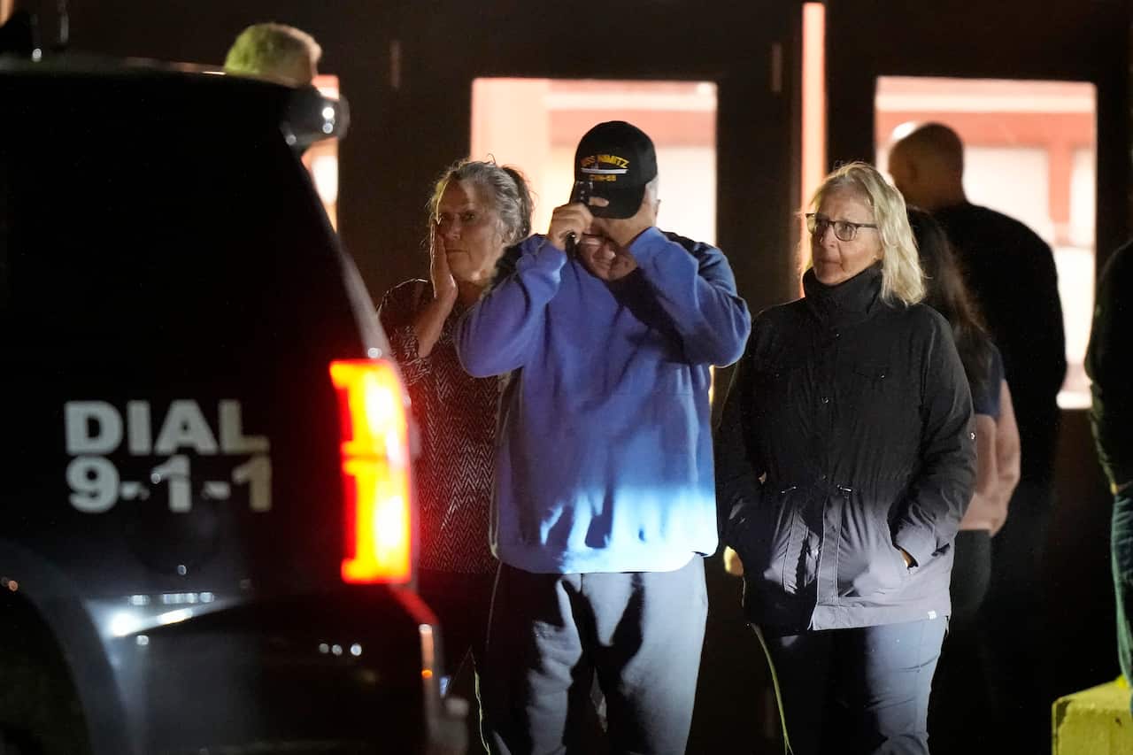 Three people walking away from a building. One has his hand covering his face.